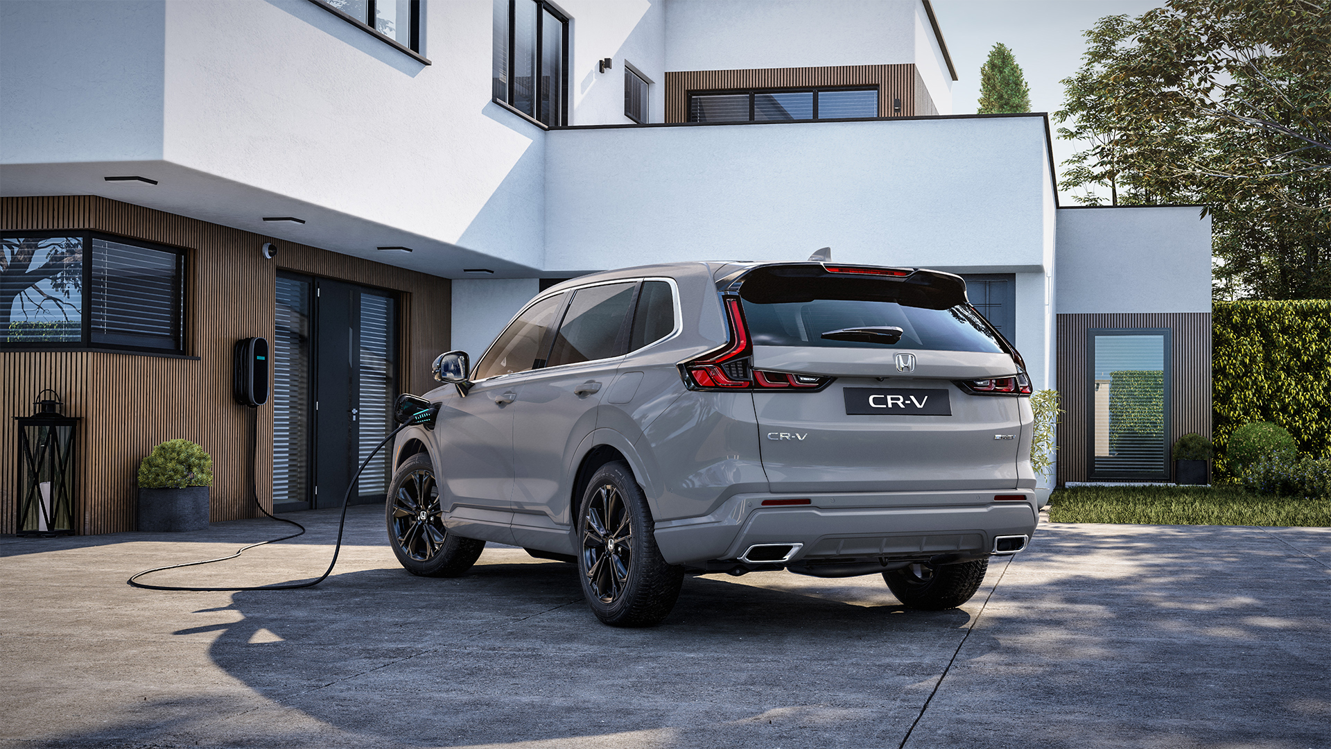 En Honda CR-V Plug-in Hybrid som er tilkoblet for lading, sett skrått bakfra.